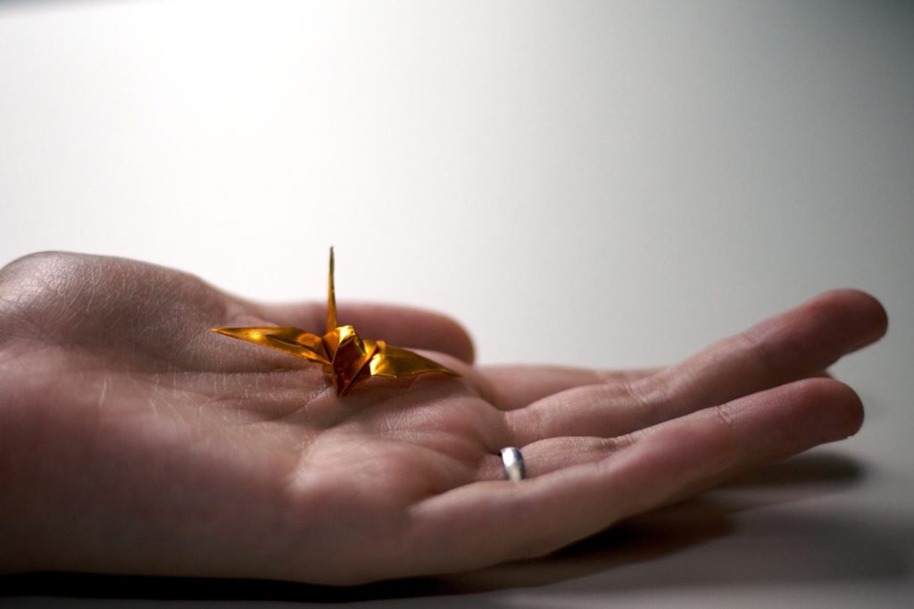 hand holding a golden origami crane